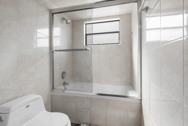 bathroom with tiled shower / bath combo, toilet, and tile walls