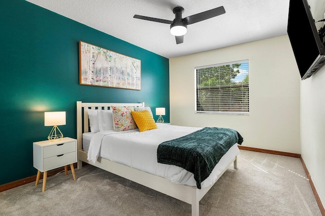 carpeted bedroom featuring a textured ceiling, baseboards, and ceiling fan