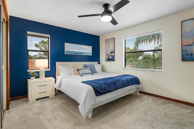 bedroom with light colored carpet, a ceiling fan, and baseboards