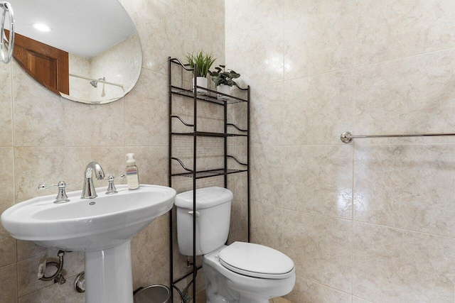 bathroom featuring toilet, tile walls, and a sink