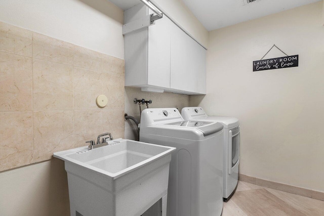 laundry area with a sink, separate washer and dryer, and cabinet space