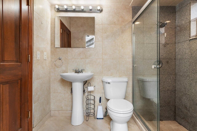 bathroom with tile walls, a shower stall, and toilet