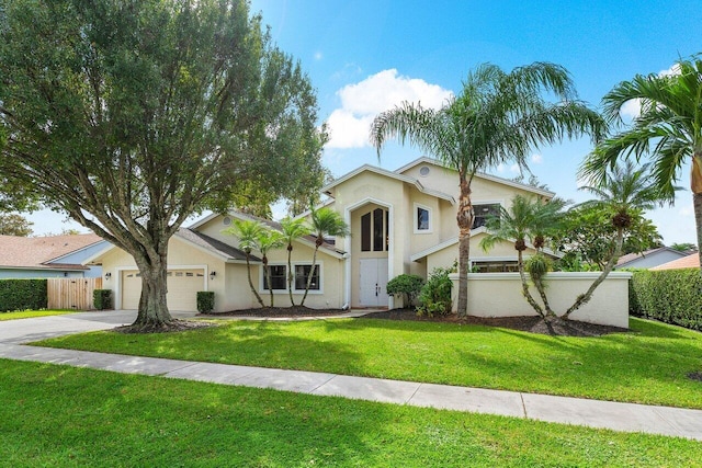 view of front of house featuring driveway, fence, a front lawn, an attached garage, and stucco siding