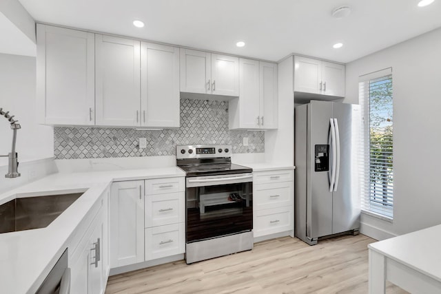 kitchen featuring white cabinets, stainless steel appliances, light countertops, a sink, and tasteful backsplash