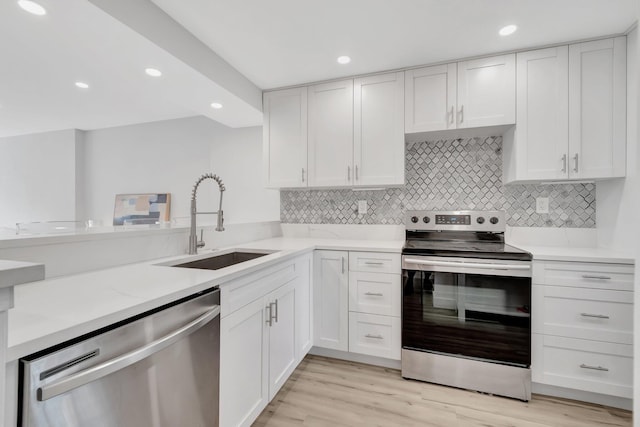 kitchen featuring stainless steel appliances, a sink, and white cabinetry