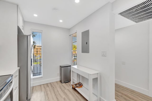 kitchen with stainless steel appliances, visible vents, light wood-type flooring, electric panel, and white cabinetry