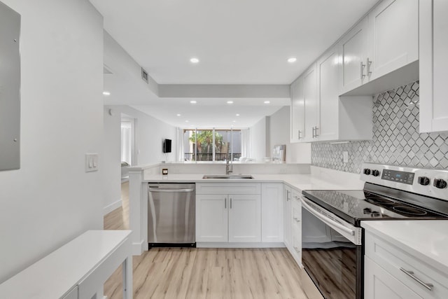 kitchen with light wood finished floors, visible vents, a sink, decorative backsplash, and appliances with stainless steel finishes