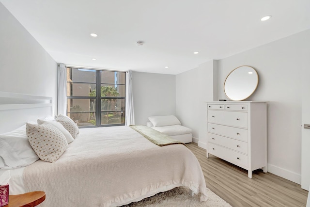 bedroom with baseboards, recessed lighting, and light wood-type flooring