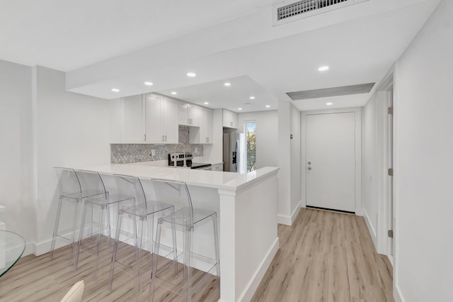 kitchen with decorative backsplash, light wood-style flooring, light countertops, a peninsula, and appliances with stainless steel finishes