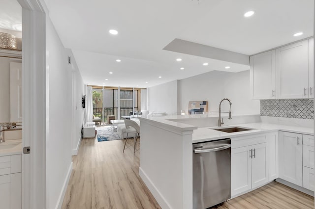 kitchen with stainless steel dishwasher, light wood-style flooring, a sink, open floor plan, and recessed lighting