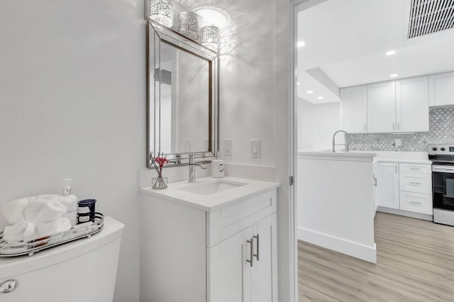 bathroom featuring wood finished floors, visible vents, toilet, vanity, and decorative backsplash