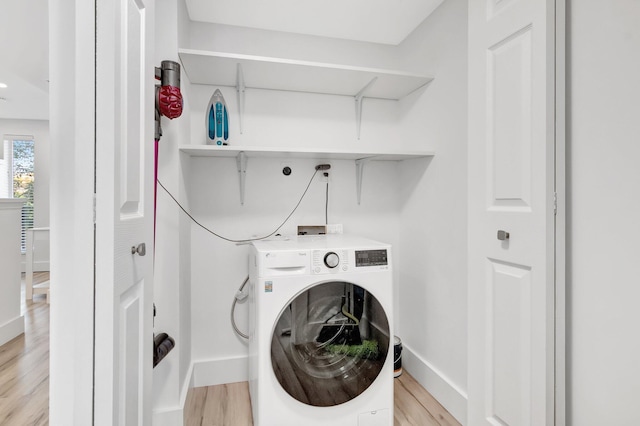 laundry area with baseboards, light wood-type flooring, laundry area, and washer / clothes dryer