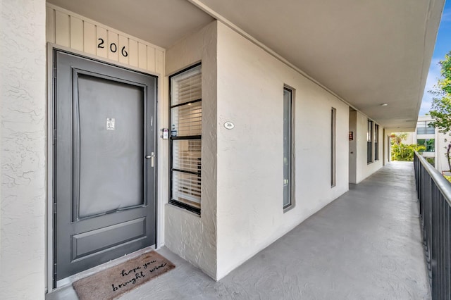 entrance to property featuring a balcony and stucco siding
