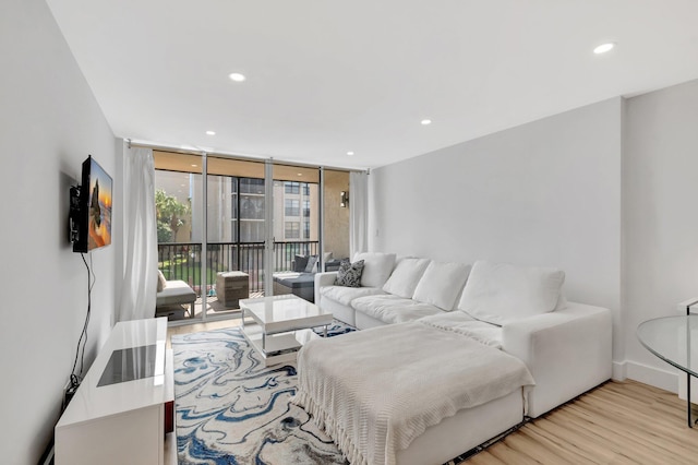 living room featuring expansive windows, baseboards, light wood-style floors, and recessed lighting