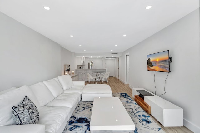 living room with recessed lighting, light wood-style flooring, visible vents, and baseboards