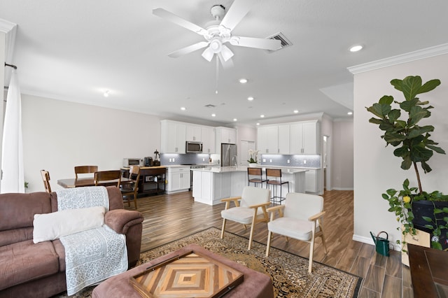 living area featuring dark wood-style floors, a ceiling fan, recessed lighting, ornamental molding, and baseboards