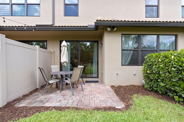 back of property with stucco siding, a patio area, fence, and outdoor dining space