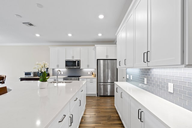 kitchen with appliances with stainless steel finishes, a sink, crown molding, light countertops, and dark wood finished floors
