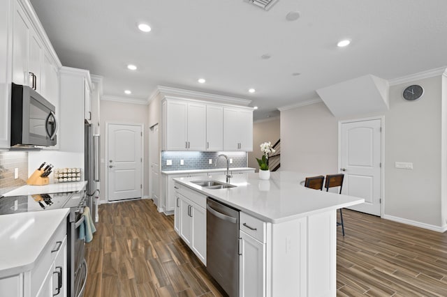 kitchen featuring appliances with stainless steel finishes, a sink, crown molding, a breakfast bar area, and decorative backsplash