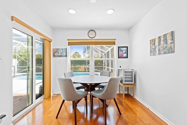 dining space with baseboards, a wealth of natural light, a textured ceiling, and light wood-type flooring