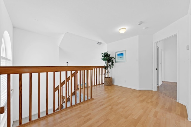 hallway featuring baseboards, wood finished floors, and visible vents
