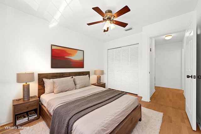 bedroom featuring light wood-style flooring, baseboards, visible vents, a ceiling fan, and a closet