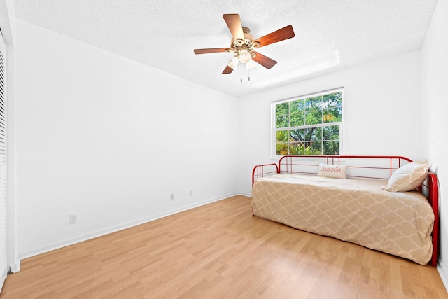 bedroom with wood finished floors, a textured ceiling, a closet, and ceiling fan