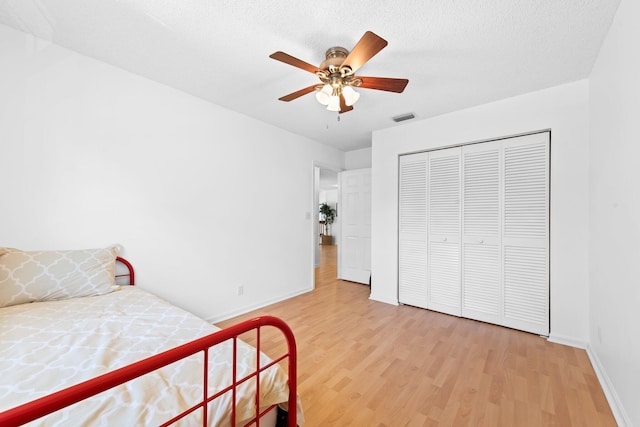 bedroom with a ceiling fan, a closet, light wood finished floors, baseboards, and visible vents