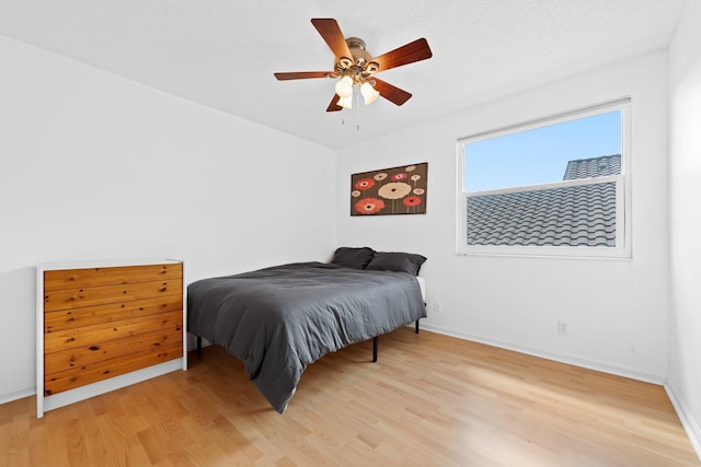 bedroom featuring light wood finished floors, a ceiling fan, and baseboards