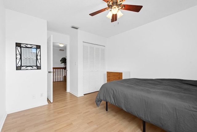 bedroom featuring light wood-type flooring, baseboards, visible vents, a closet, and ceiling fan