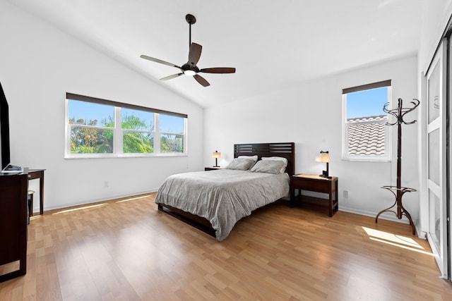 bedroom with ceiling fan, vaulted ceiling, multiple windows, and light wood-type flooring