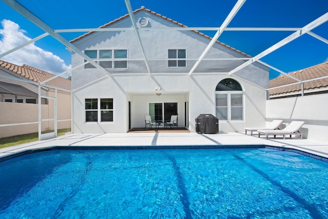 outdoor pool with a lanai, a patio, and a grill