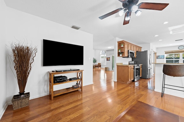 living room featuring recessed lighting, visible vents, a ceiling fan, baseboards, and light wood-style flooring