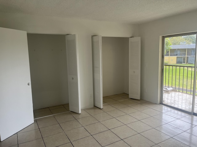1626 Meadows Cir W Unit 1626, Boynton Beach, FL 33436 - unfurnished bedroom with access to outside, a textured ceiling, light tile patterned flooring, and a closet