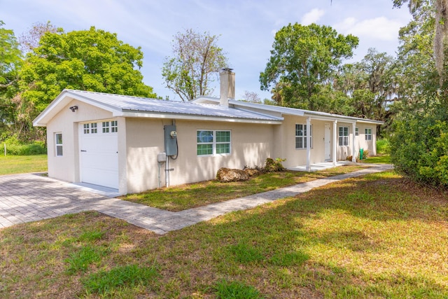 2675 SW 24th Ave, Okeechobee, FL 34974 - ranch-style home with stucco siding, a chimney, metal roof, a front lawn, and a garage