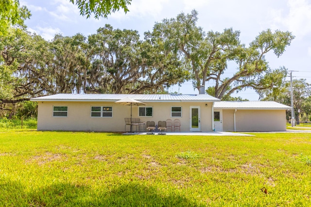 2675 SW 24th Ave, Okeechobee, FL 34974 - rear view of house with a patio, a lawn, stucco siding, and metal roof