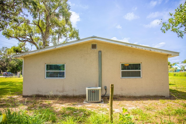 2675 SW 24th Ave, Okeechobee, FL 34974 - view of side of home featuring cooling unit, stucco siding, and a lawn