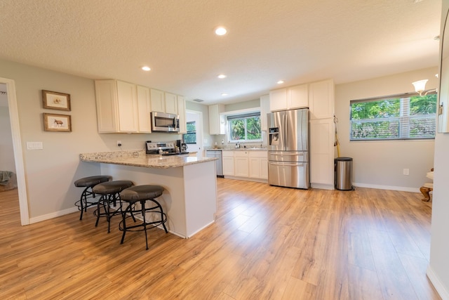 2675 SW 24th Ave, Okeechobee, FL 34974 - kitchen featuring stainless steel appliances, light wood finished floors, a peninsula, white cabinets, and recessed lighting