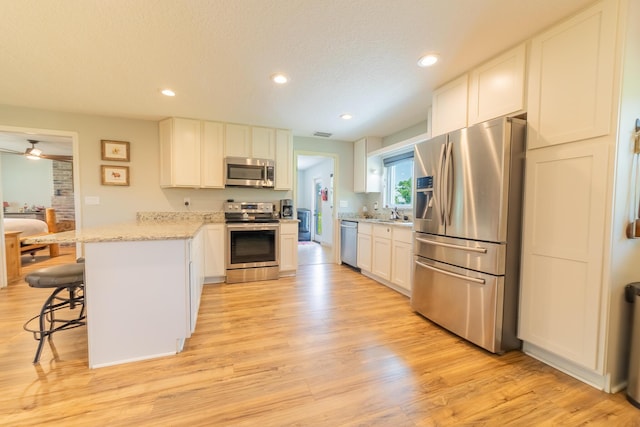 2675 SW 24th Ave, Okeechobee, FL 34974 - kitchen with stainless steel appliances, a peninsula, light wood finished floors, white cabinets, and recessed lighting
