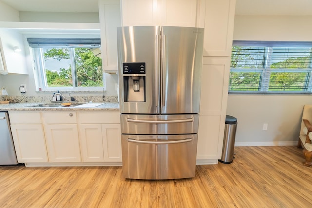 2675 SW 24th Ave, Okeechobee, FL 34974 - kitchen featuring appliances with stainless steel finishes, white cabinetry, light wood finished floors, light stone counters, and a sink