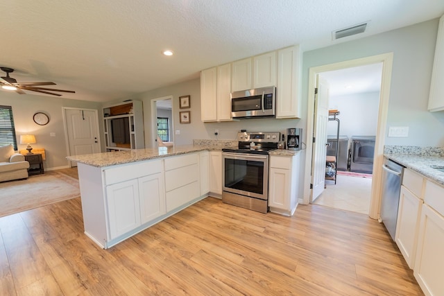 2675 SW 24th Ave, Okeechobee, FL 34974 - kitchen featuring appliances with stainless steel finishes, a peninsula, open floor plan, light wood finished floors, and a ceiling fan