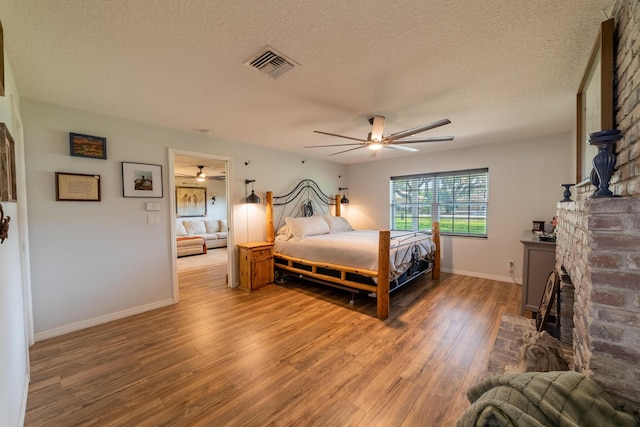 2675 SW 24th Ave, Okeechobee, FL 34974 - bedroom featuring wood finished floors, baseboards, a textured ceiling, a ceiling fan, and a fireplace