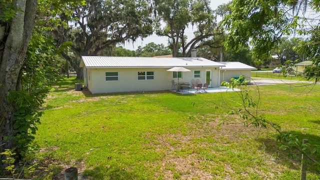 2675 SW 24th Ave, Okeechobee, FL 34974 - back of property featuring stucco siding, a patio, a yard, central air condition unit, and metal roof