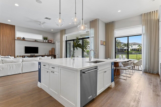 kitchen featuring visible vents, a center island with sink, wood finished floors, dishwasher, and a sink