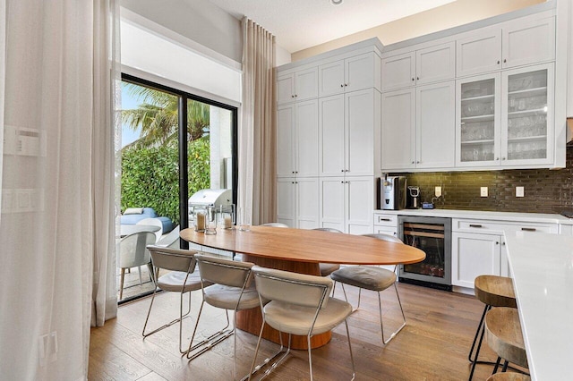 dining room featuring beverage cooler, a dry bar, and light wood-style floors
