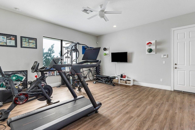 workout area featuring a ceiling fan, a textured ceiling, visible vents, wood finished floors, and baseboards