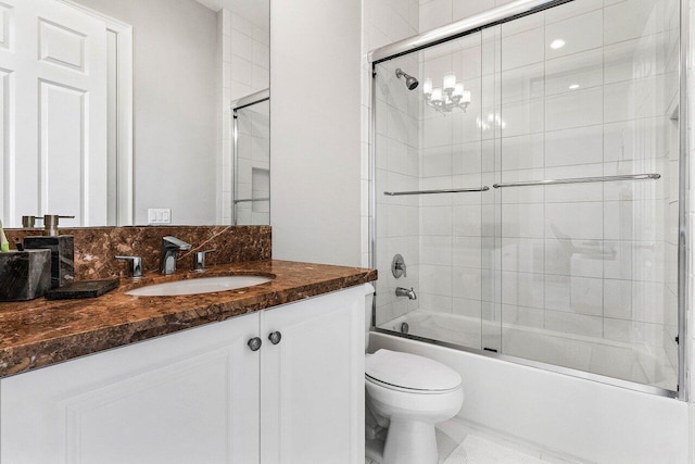 bathroom featuring vanity, bath / shower combo with glass door, and toilet