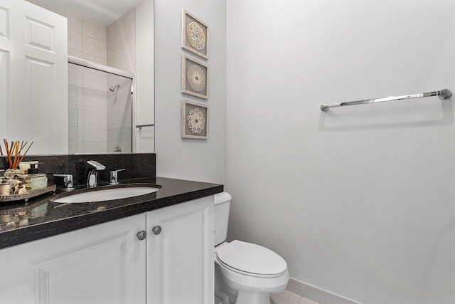 bathroom featuring toilet, baseboards, tiled shower, and vanity