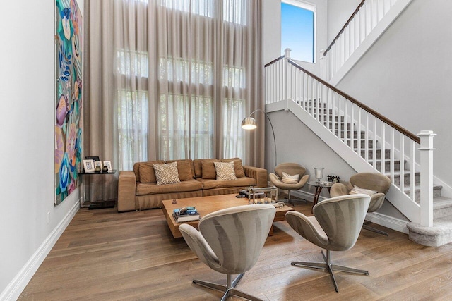 living room featuring baseboards, wood finished floors, and stairway