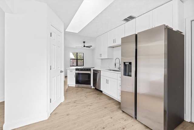 kitchen with a sink, light wood-type flooring, white cabinets, appliances with stainless steel finishes, and visible vents